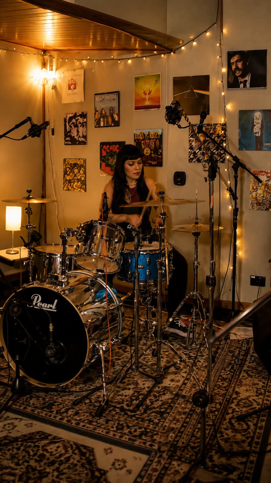 Baterista tocando em estúdio com pôsteres de rock na parede